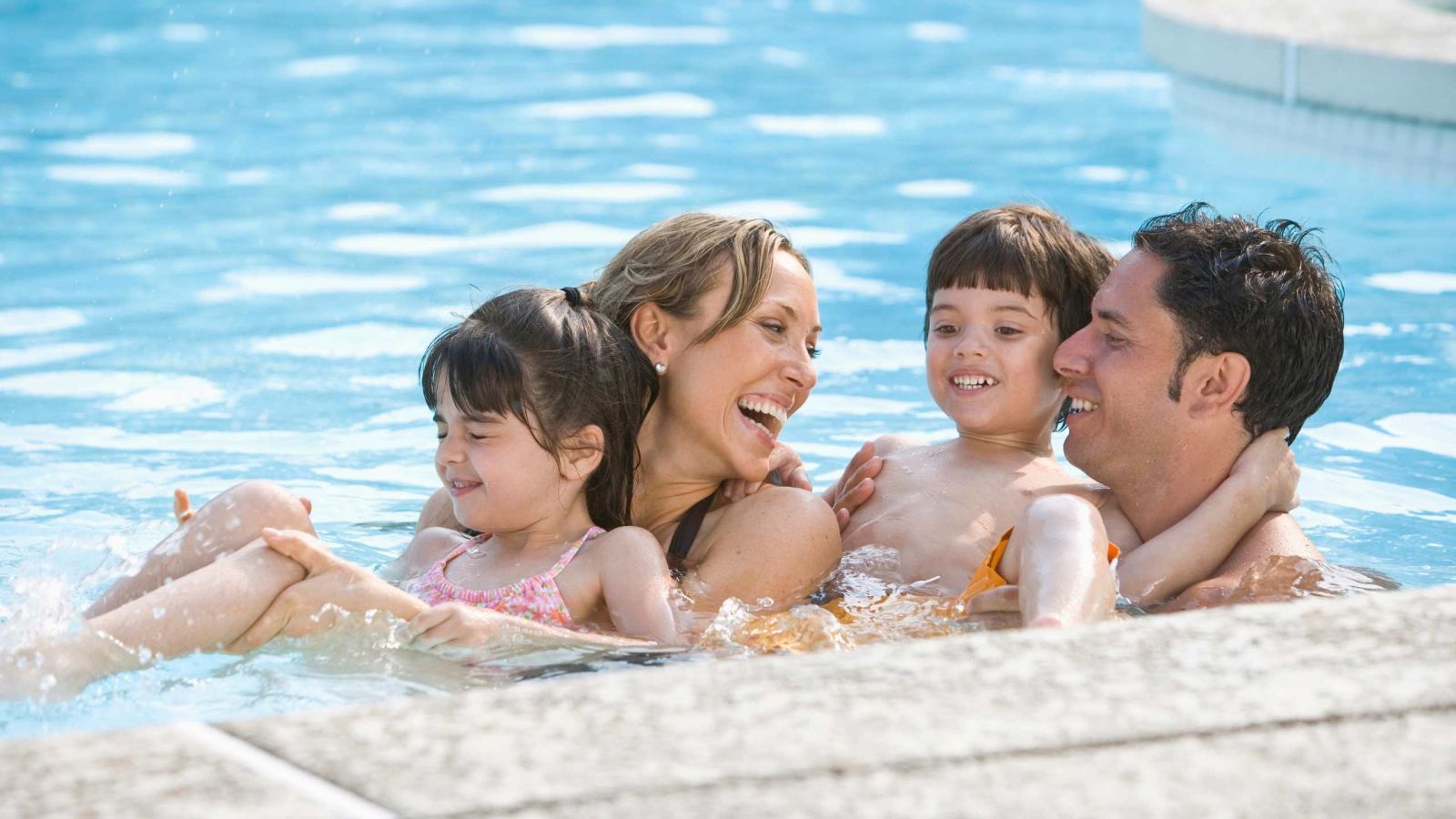 family happily playing in pool