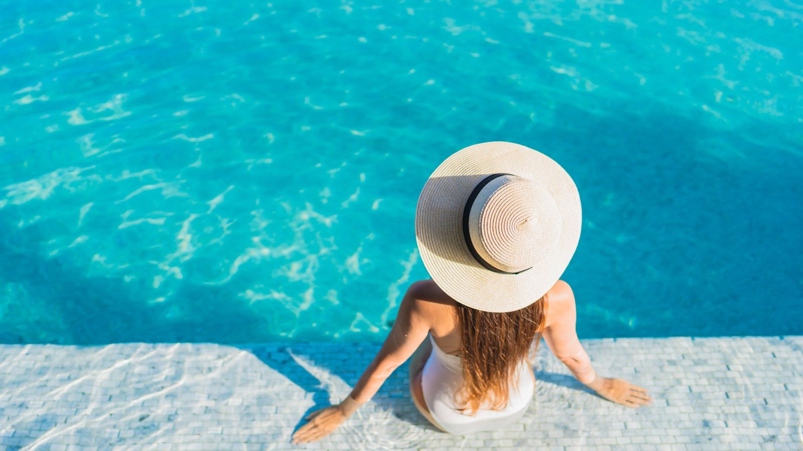 woman with hat relaxing by pool